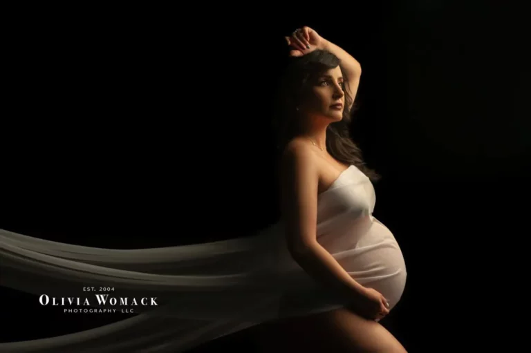 Pregnant woman in flowing white dress posing dramatically