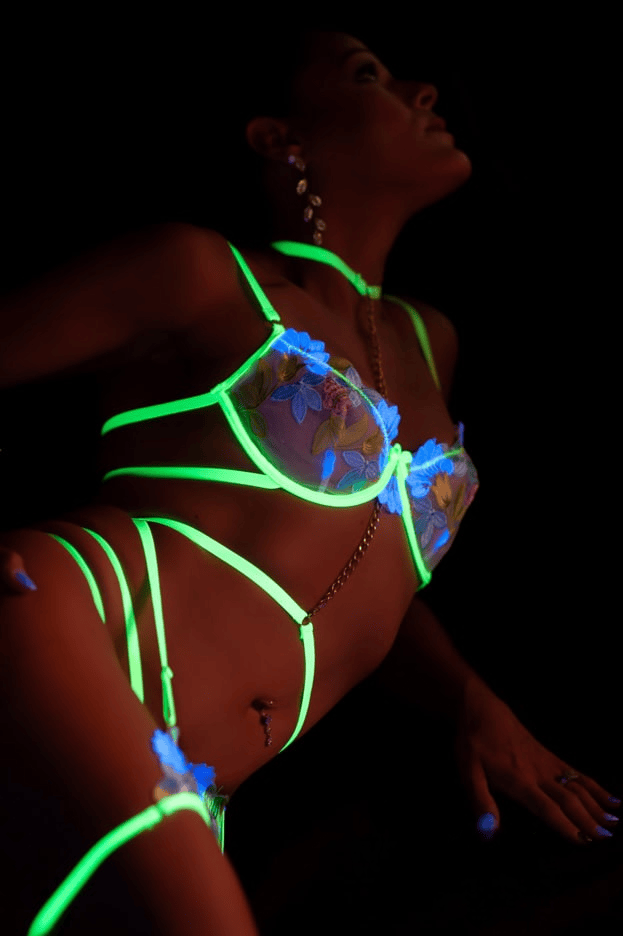 Woman wearing glowing neon lingerie in the dark
