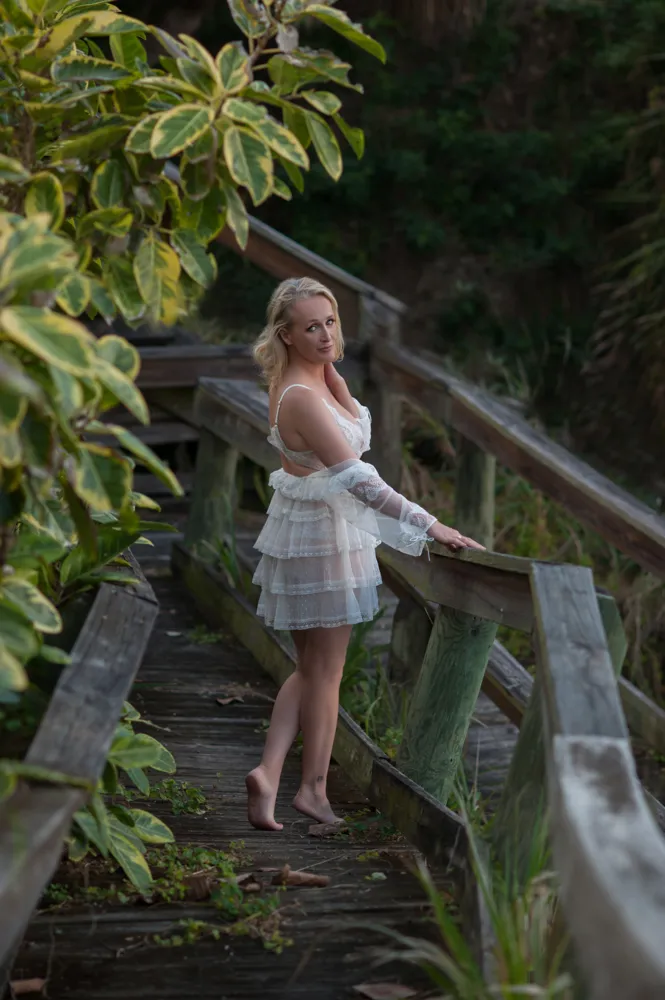 Woman in white dress on rustic wooden bridge