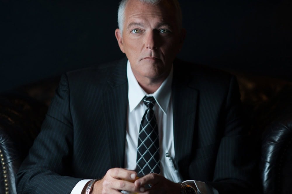Serious businessman in dark suit sitting on leather couch