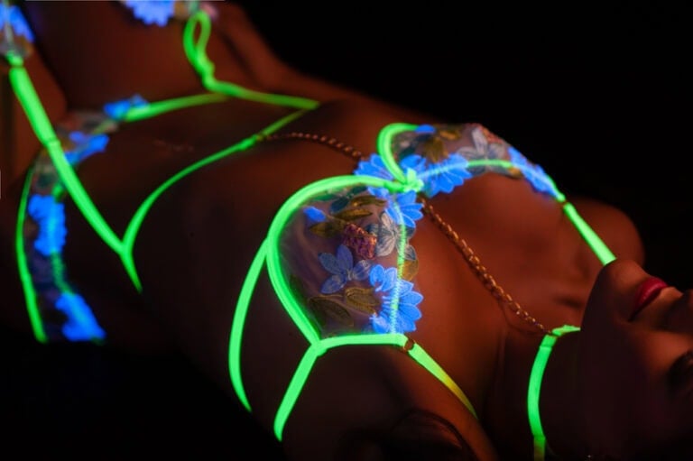 Neon lights outline woman's figure in artistic photography.